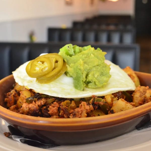 A Tchotchke breakfast bowl with chorizo, potatoes, a fried egg, jalapeños, and guacamole.